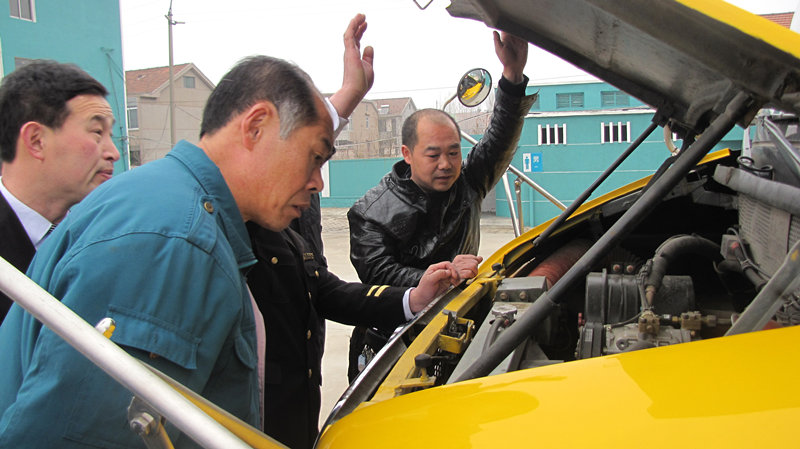 檢車人員正在查看校車發(fā)動(dòng)機(jī)是否正常