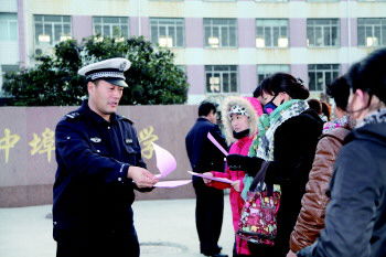 交警在學校門口向家長發放校車安全宣傳單(資料片)。